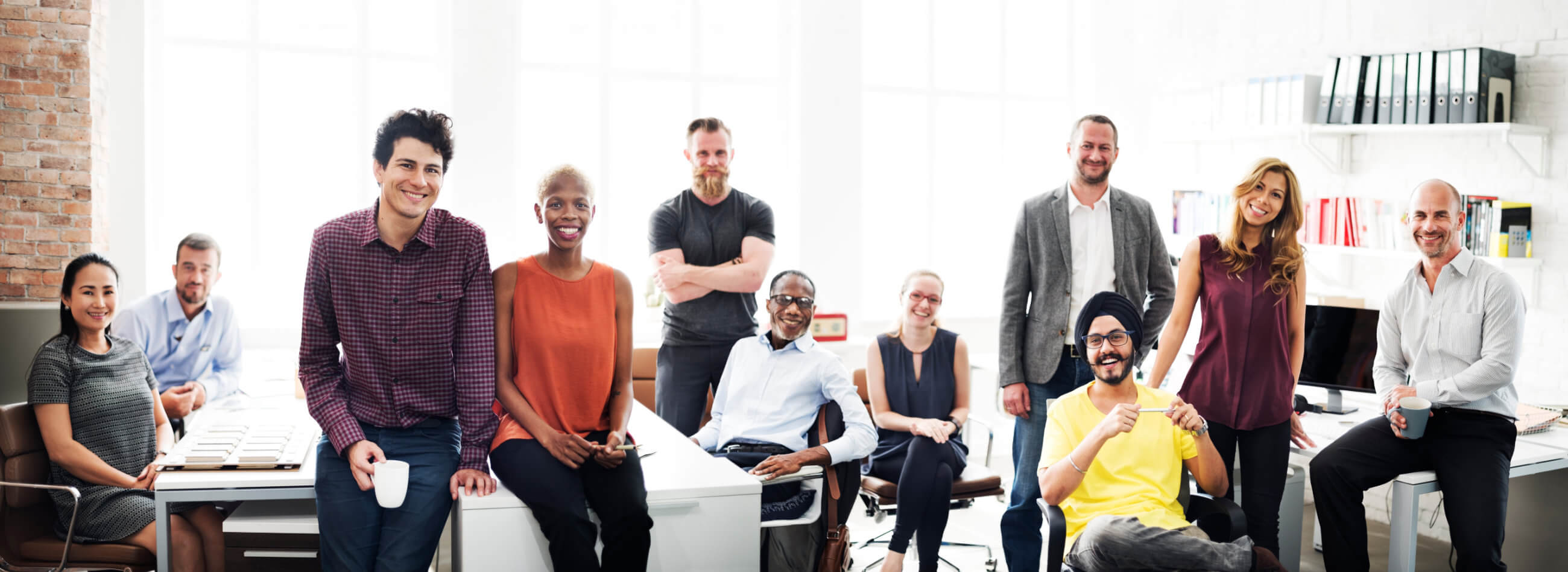 a group of people in an office room smiling toward the camera