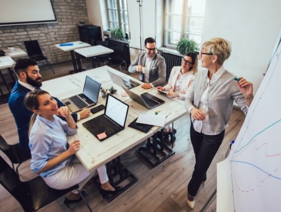 staff members in a conference room looking at a graph on the board