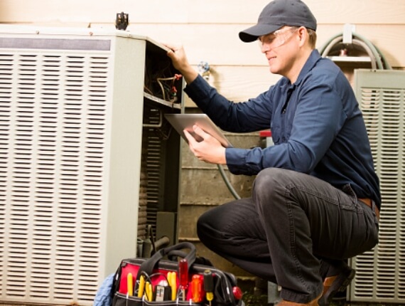 tool bag next to a maintenance worker checking the air conditioning unit