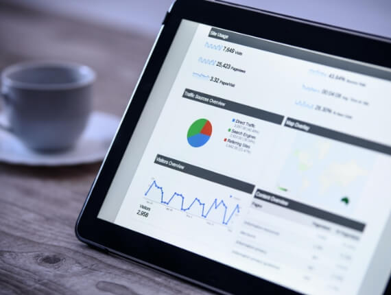 tablet device showing graph reports with a coffee cup placed behind