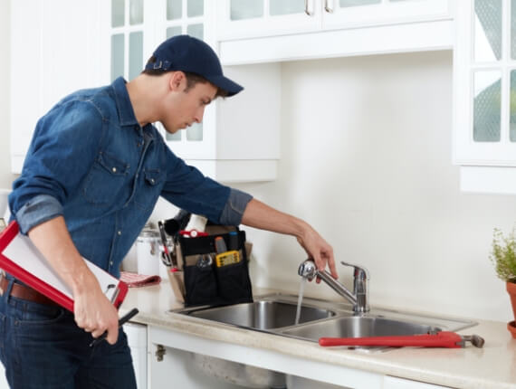 a contractor holding a pen and a clipboard checking the sink